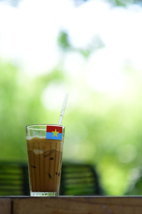 Free A glass of Vietnamese iced coffee with a flag sits outdoors in a bright setting. Stock Photo