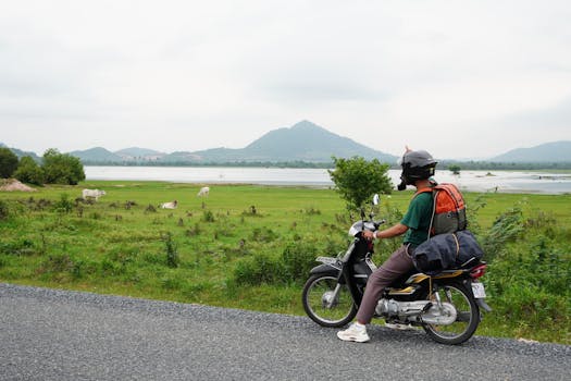 A traveler on a motorcycle enjoys the scenic view of the Kampot countryside, Cambodia.