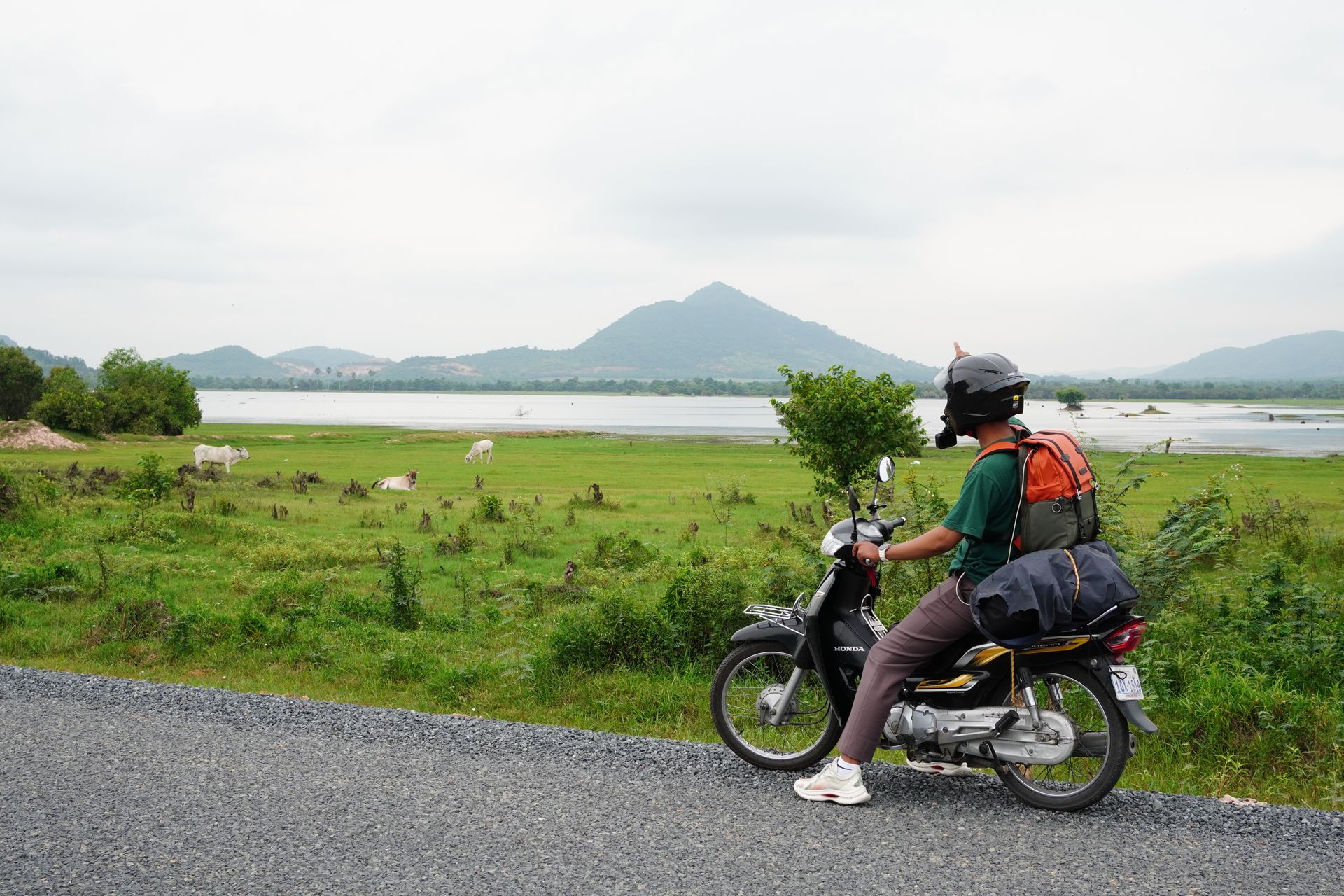 Motorcyclist riding through rural countryside near Kampot, Cambodia
