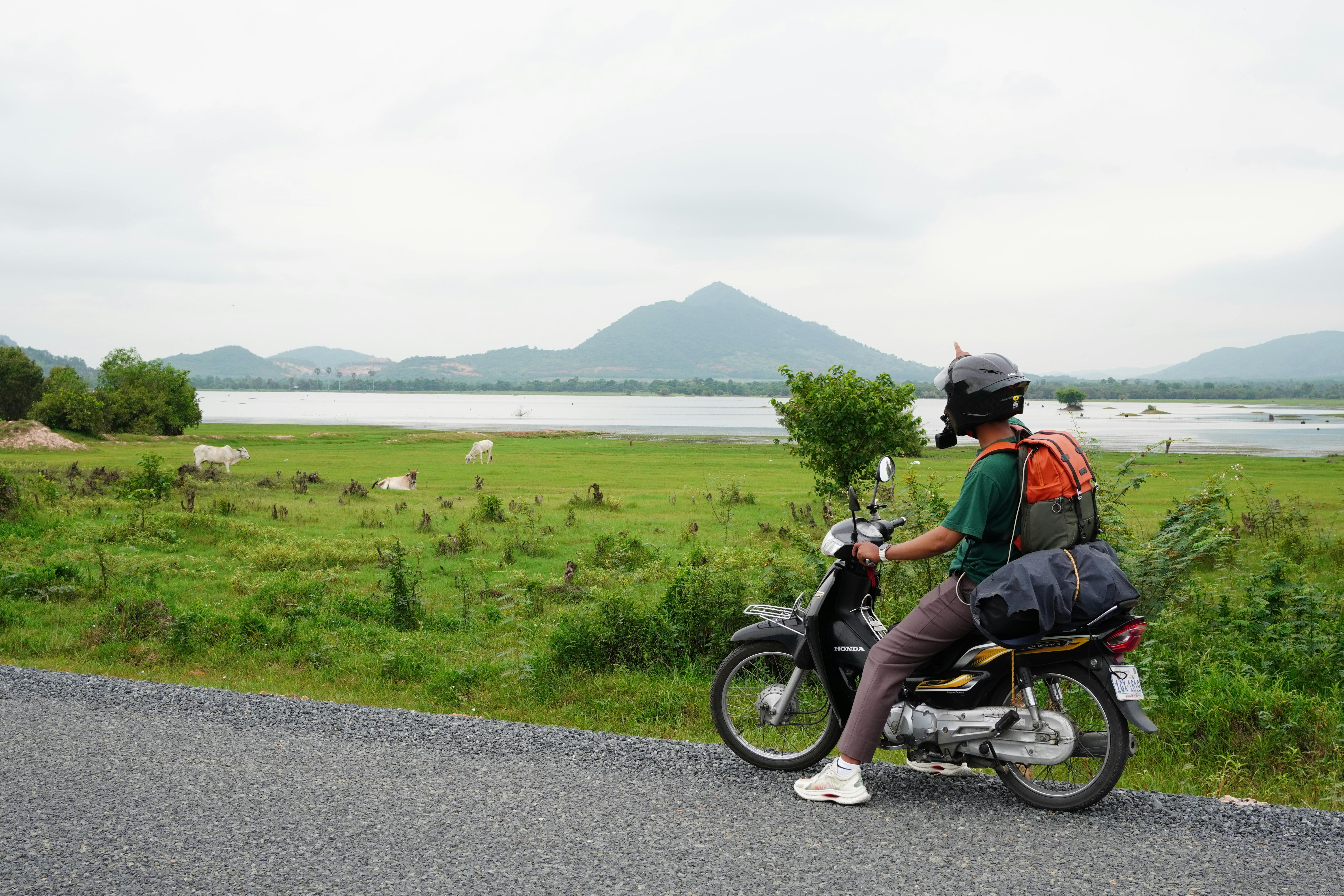 Motorcyclist Exploring Rural Landscape in Cambodia · Free Stock Photo