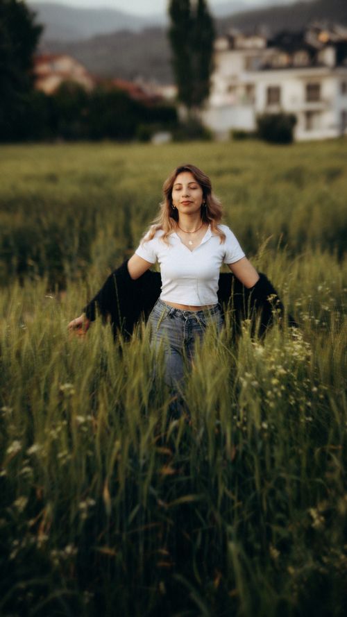 Free Woman gracefully enjoying a serene moment in a lush green field. Stock Photo