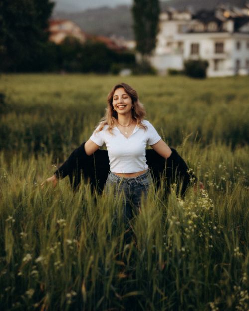 Free Smiling woman with open arms enjoying nature in a lush green meadow. Stock Photo