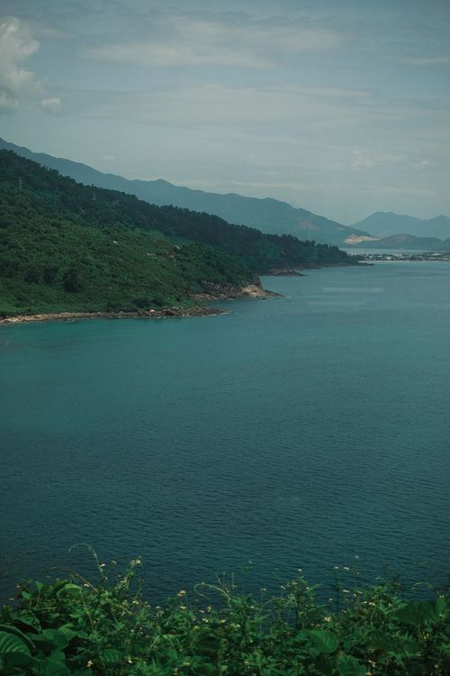 Free Scenic view of green hills meeting the calm blue sea in Hội An, Vietnam Stock Photo