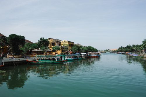 Free Quaint river scene with traditional boats in Hội An, capturing vibrant architecture and serene water. Stock Photo