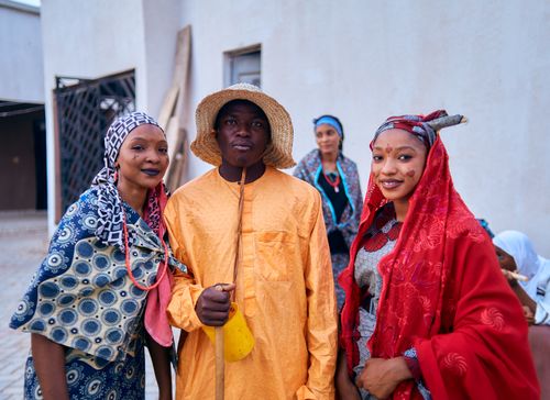 Free Group of Nigerian adults celebrating in colorful traditional attire outdoors. Stock Photo