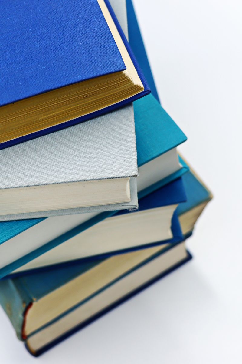 A vertical stack of books with blue covers on a white background symbolizes education and literature. A vertical stack of books with blue covers on a white background symbolizes education and literature.