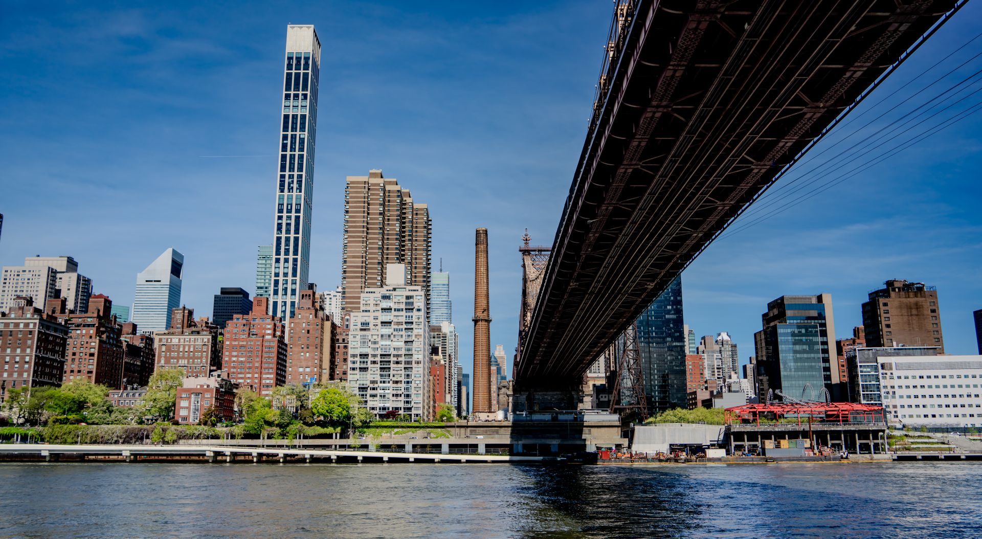 Captivating view of New York City's skyline beneath a bridge, showcasing skyscrapers and city life.