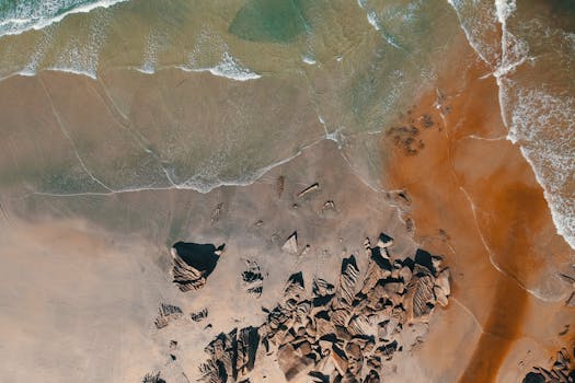 Drone shot capturing a stunning aerial view of a rocky coastline in Kijal, Malaysia, with vibrant colors and clear waters.