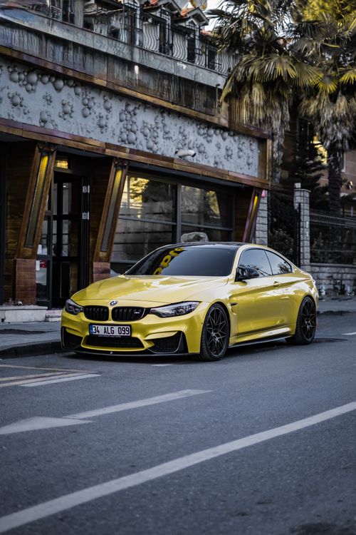 Free A sleek yellow sports car is parked by a modern building in an urban setting, showcasing elegance and style. Stock Photo