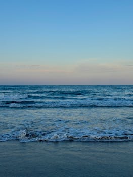 Tranquil evening waves at a beach in Alicante, Spain with a serene sky.