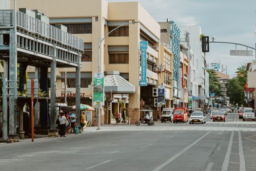 Vibrant urban street in Davao City, featuring pedestrians, vehicles, and local architecture on a sunny day.