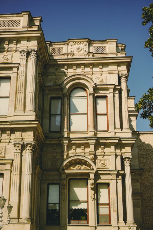 Free Detailed view of a historic building facade with ornate columns and arches in bright sunlight. Stock Photo