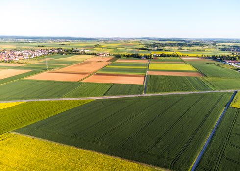 Stunning aerial view of vibrant patchwork agricultural fields and a distant village.