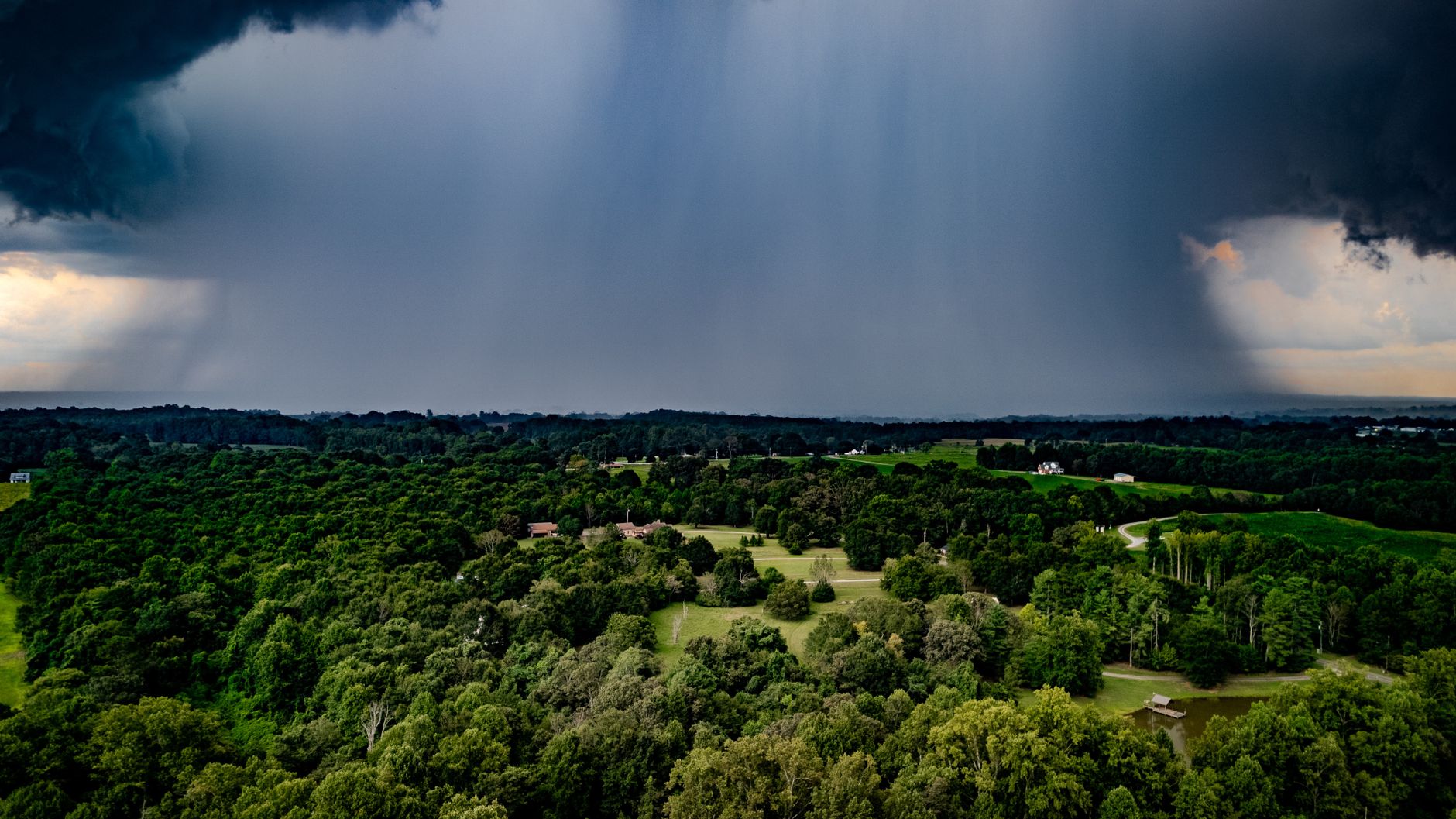 A picturesque aerial view of a storm pouring rain over lush greenery in North Carolina.