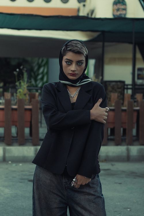 Free Fashionable woman in a dark outfit posing outdoors with a chic urban backdrop. Stock Photo