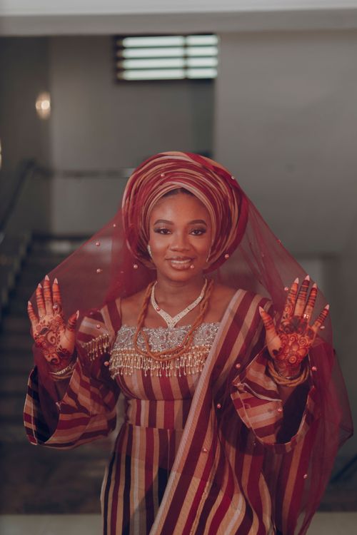 Free Smiling African woman in elegant traditional wedding attire with henna, indoors. Stock Photo