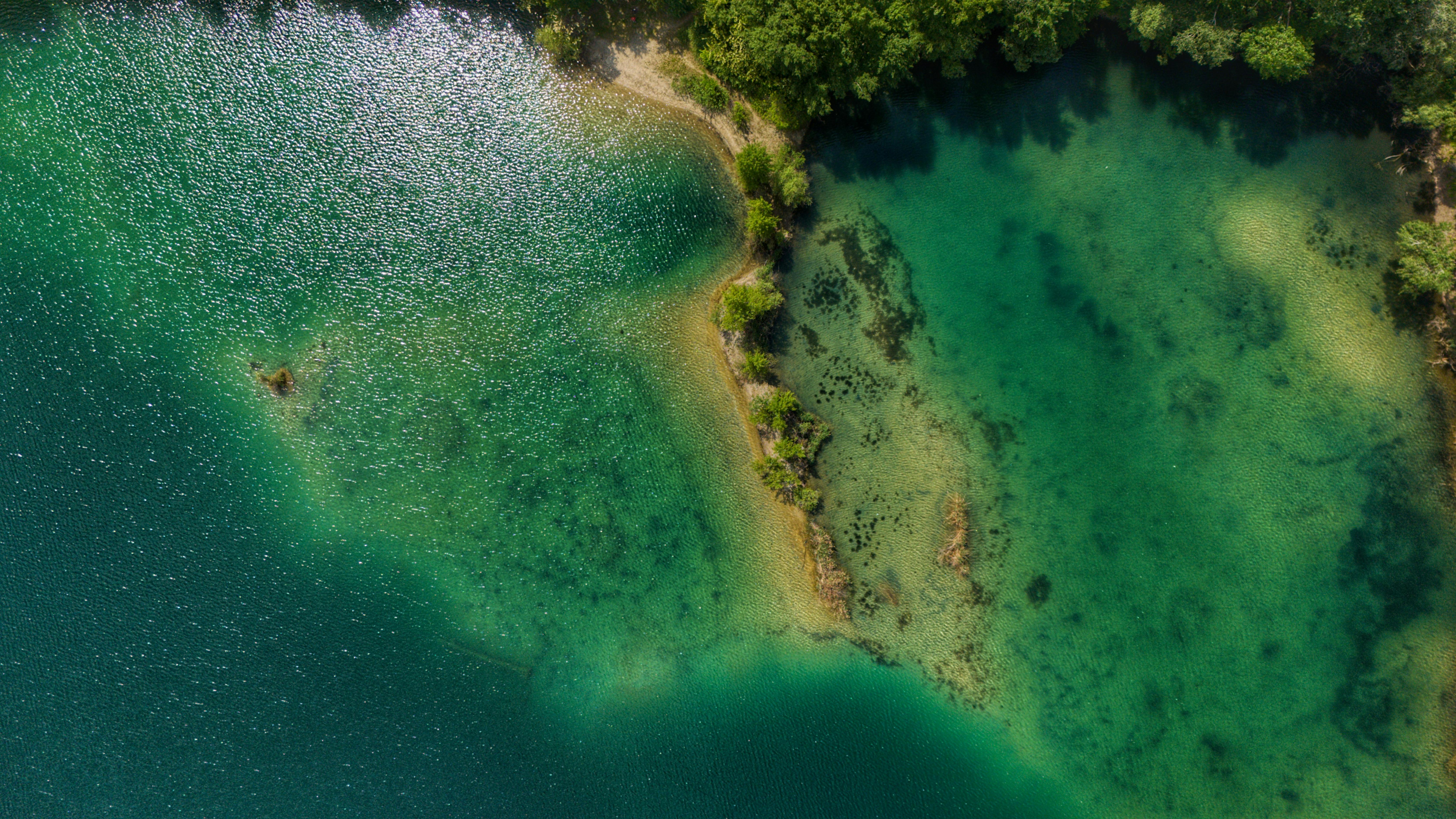 Stunning aerial view of a turquoise lake and lush green forest revealing natural beauty and tranquility.