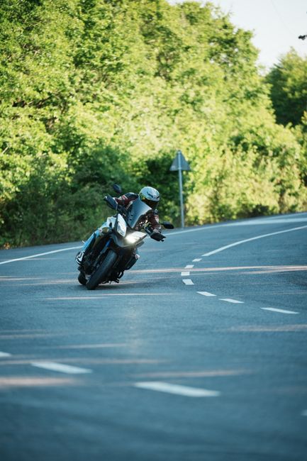 Vue de profil de la Yamaha Tracer 9 GT en mouvement sur route de col, angle dynamique montrant la bagagerie intégrée