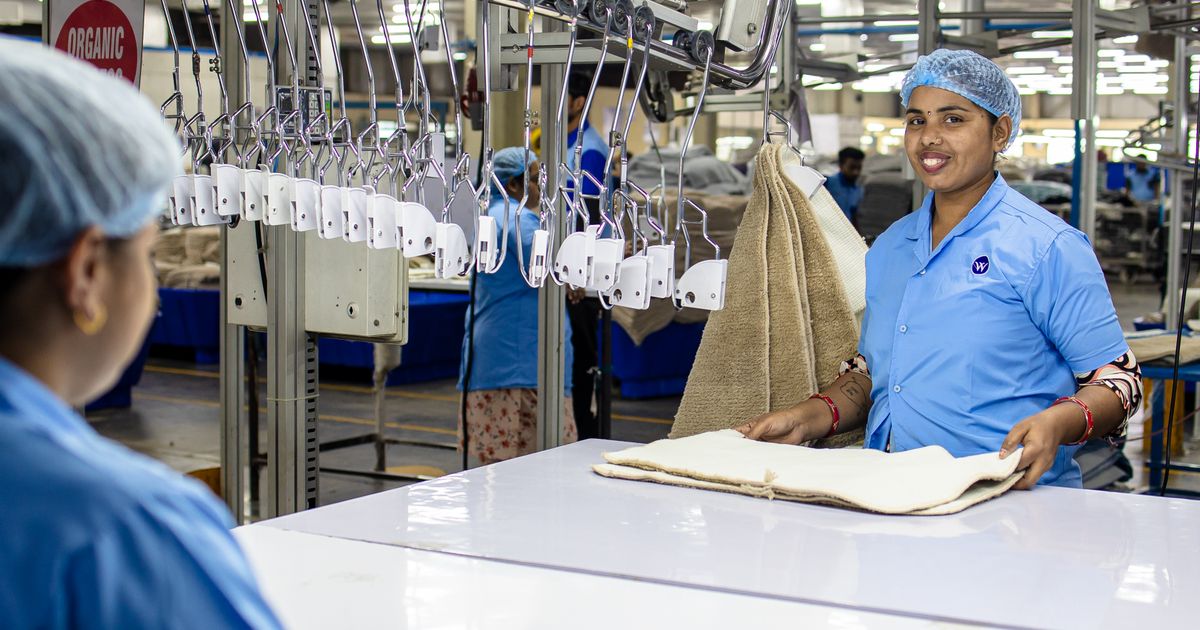 Workers in uniforms folding fabric in a textile factory.