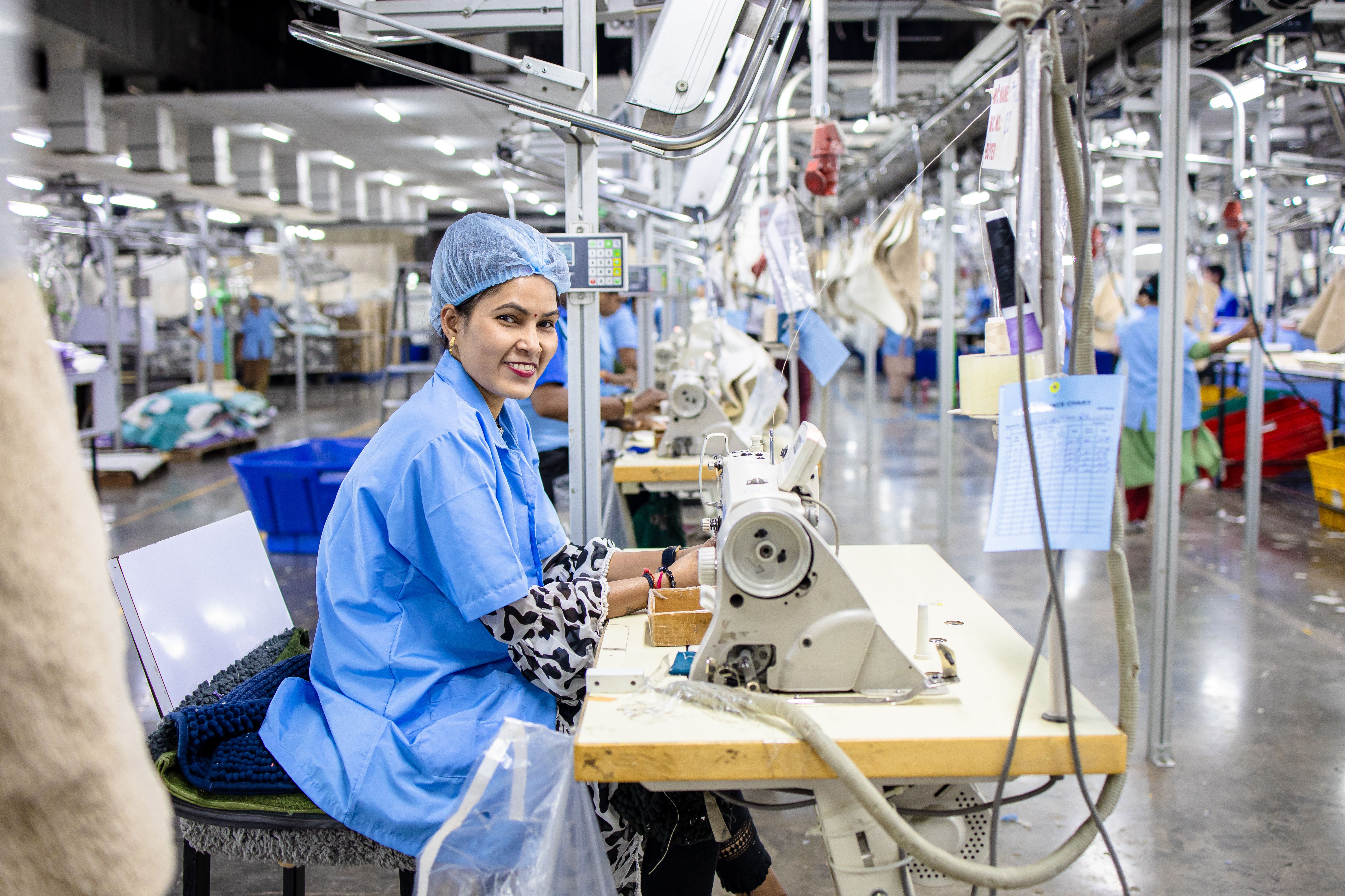 Smiling Female Worker at Sewing Machine in Factory · Free Stock Photo