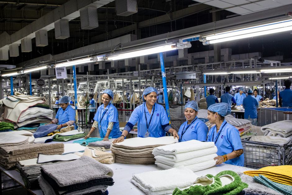 Blue-collar workers in an organized textile factory handling fabrics.