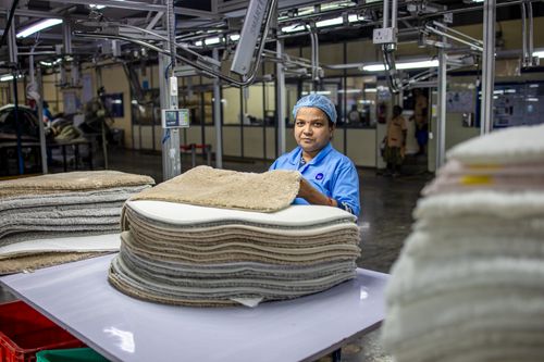Free A factory worker in a hair net processes stacked textiles in an industrial setting, showcasing precision labor. Stock Photo
