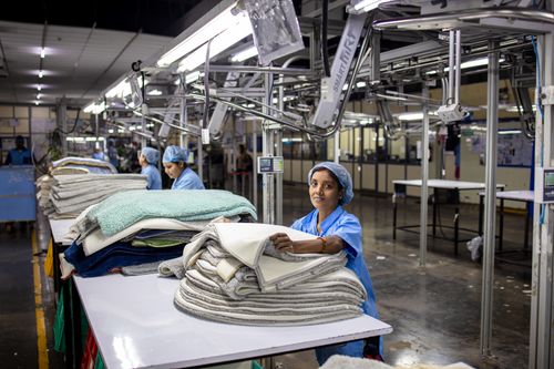 Free A female factory worker organizes textiles in an industrial setting, showcasing blue-collar work. Stock Photo