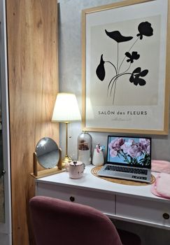 A cozy home workspace featuring modern decor, a wall art piece, and an open laptop with floral wallpaper.