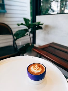 一杯盛在蓝色杯子里的特写奶油拿铁，置于咖啡桌上，营造出舒适的室内氛围