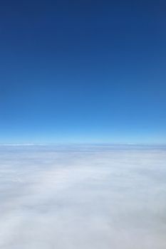 A serene view of a clear blue sky above a blanket of white clouds.