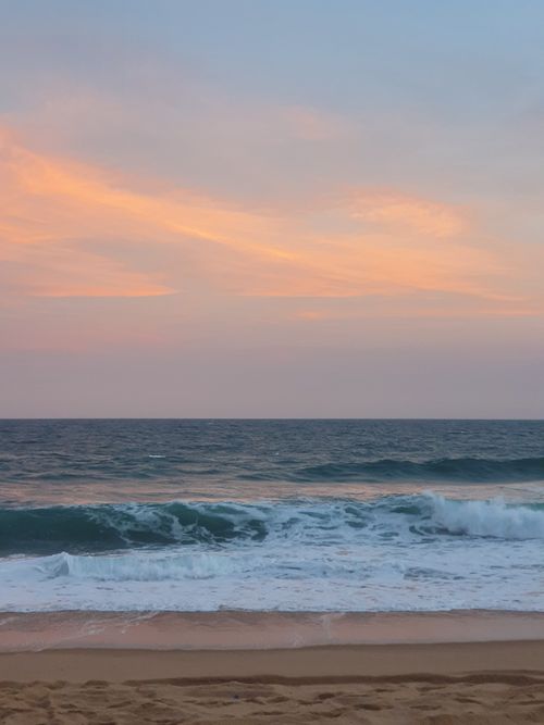Free Calm waves and vibrant sunset sky at Praia Do Bilene, Mozambique. Stock Photo
