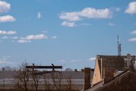 Silhouetted workers on a roof with clear blue sky and clouds in the background.