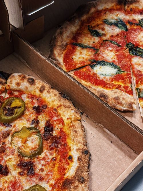 Free Two artisan pizzas in cardboard boxes with fresh toppings, perfect for a casual meal. Stock Photo