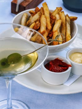 Chic outdoor dining in Atlanta with martini, fries, and dips offering a vibrant culinary experience.