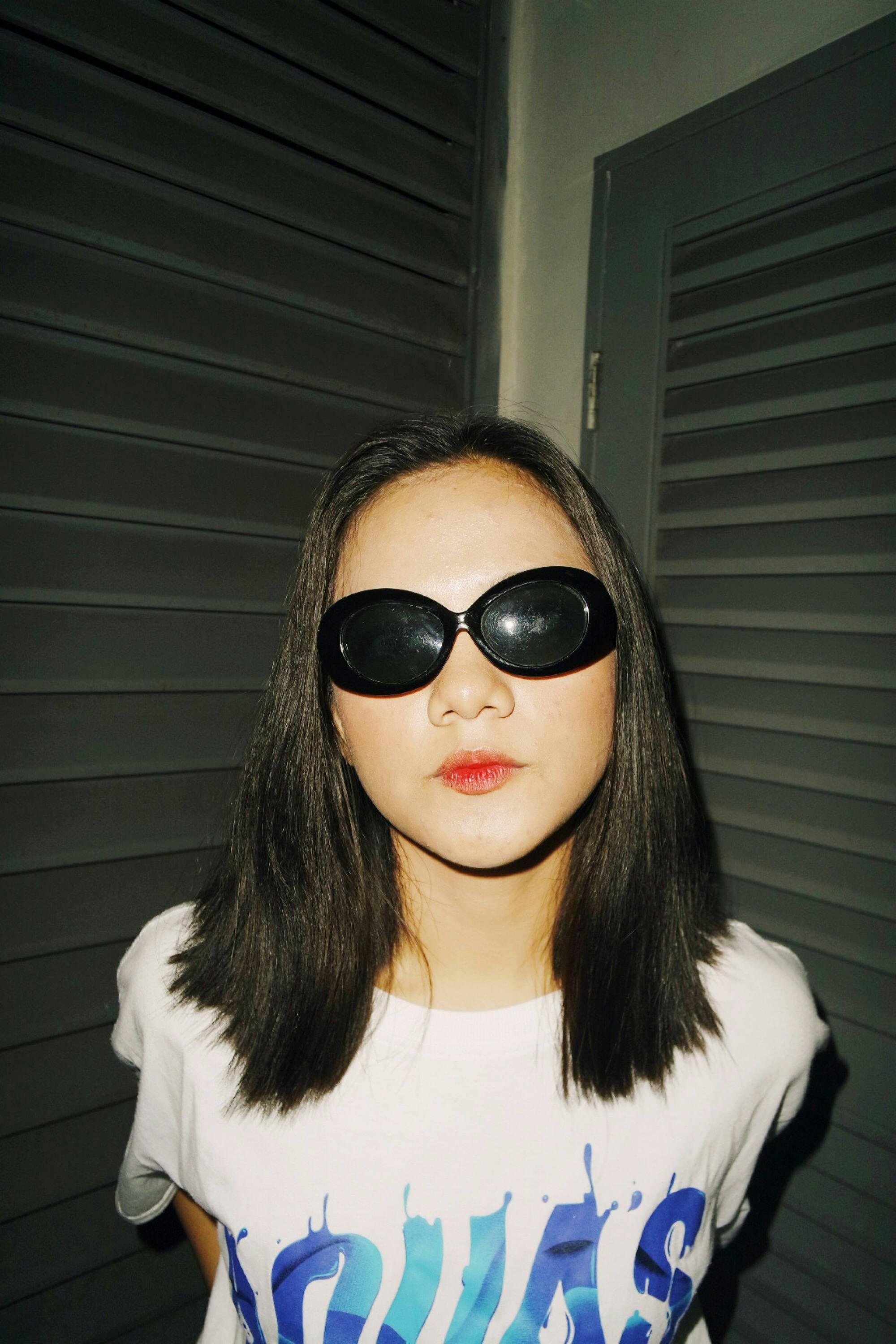 一位时尚的年轻女子戴着太阳镜，在现代室内环境中摆出姿势，散发着风格与自信