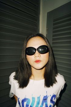 一位时尚的年轻女子戴着太阳镜，在现代室内环境中摆出姿势，散发着风格与自信