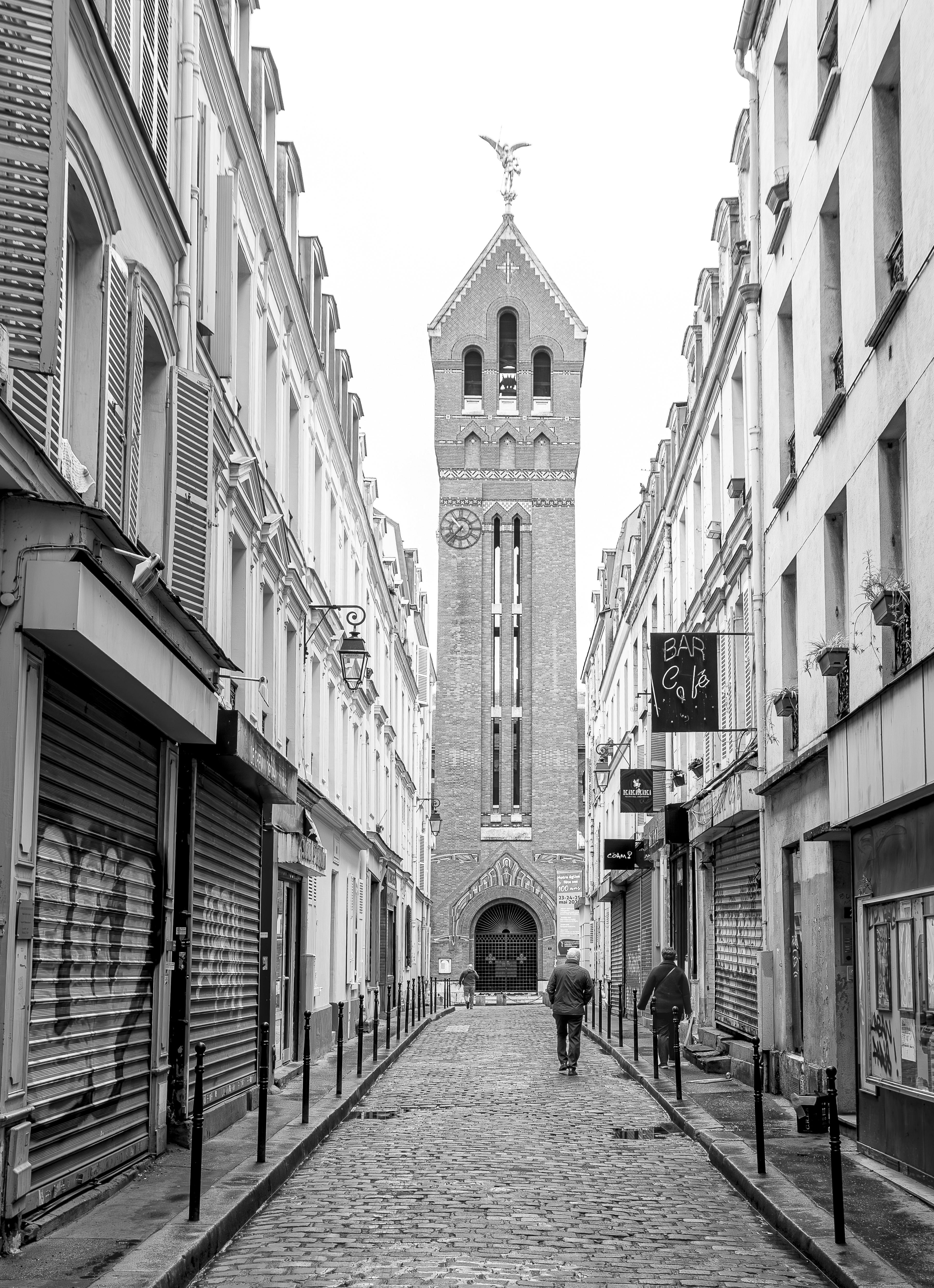 Monochrome view of a cobblestone street with a historic tower in the background.