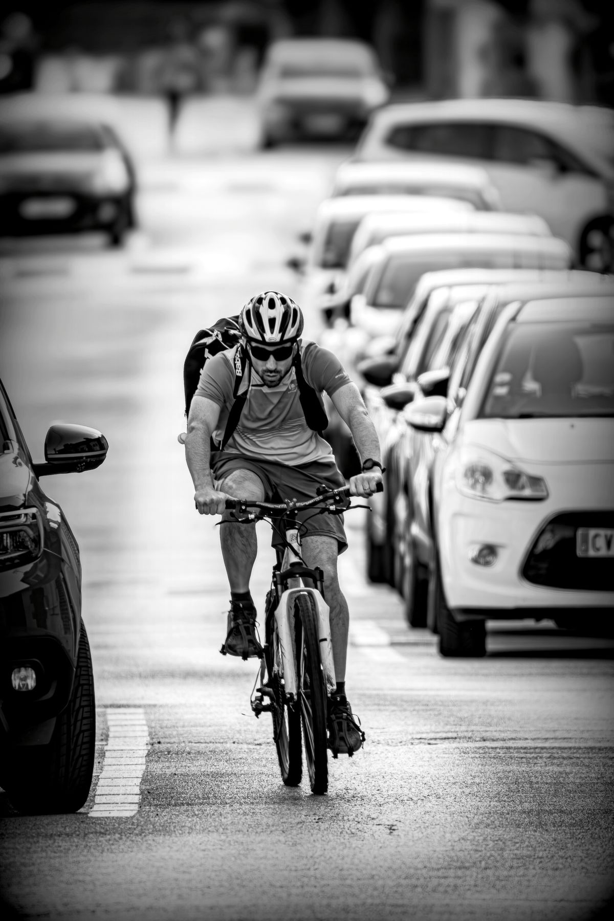 Cyclist navigating a busy urban street with parked vehicles