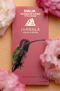 Vibrant Jangala chocolate bar surrounded by pink flowers, evoking luxury and artisanal craftsmanship.