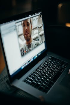 Close-up of a person engaged in a video call on a laptop indoors, showcasing modern technology.