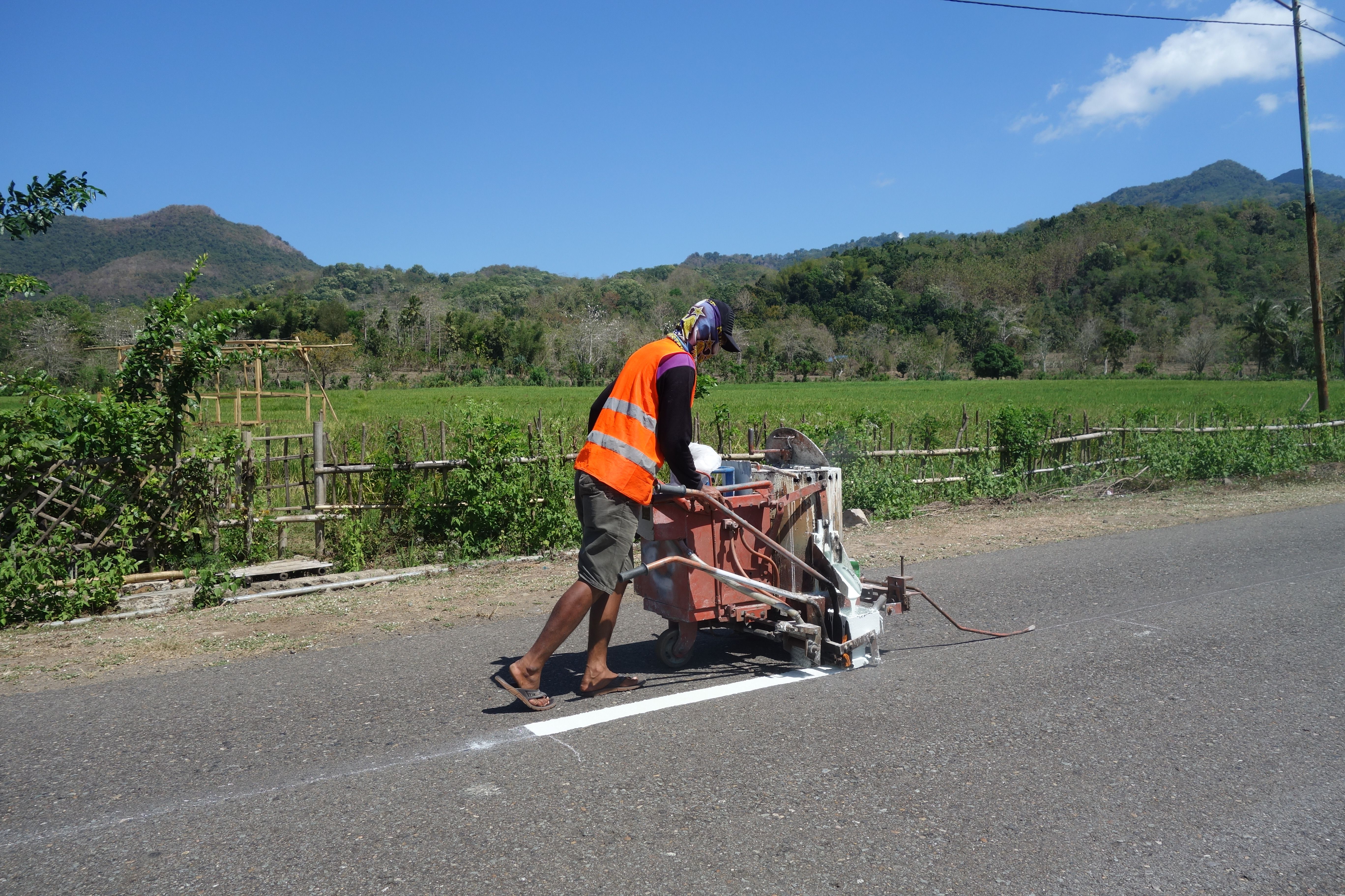 Worker painting road lines on a sunny day