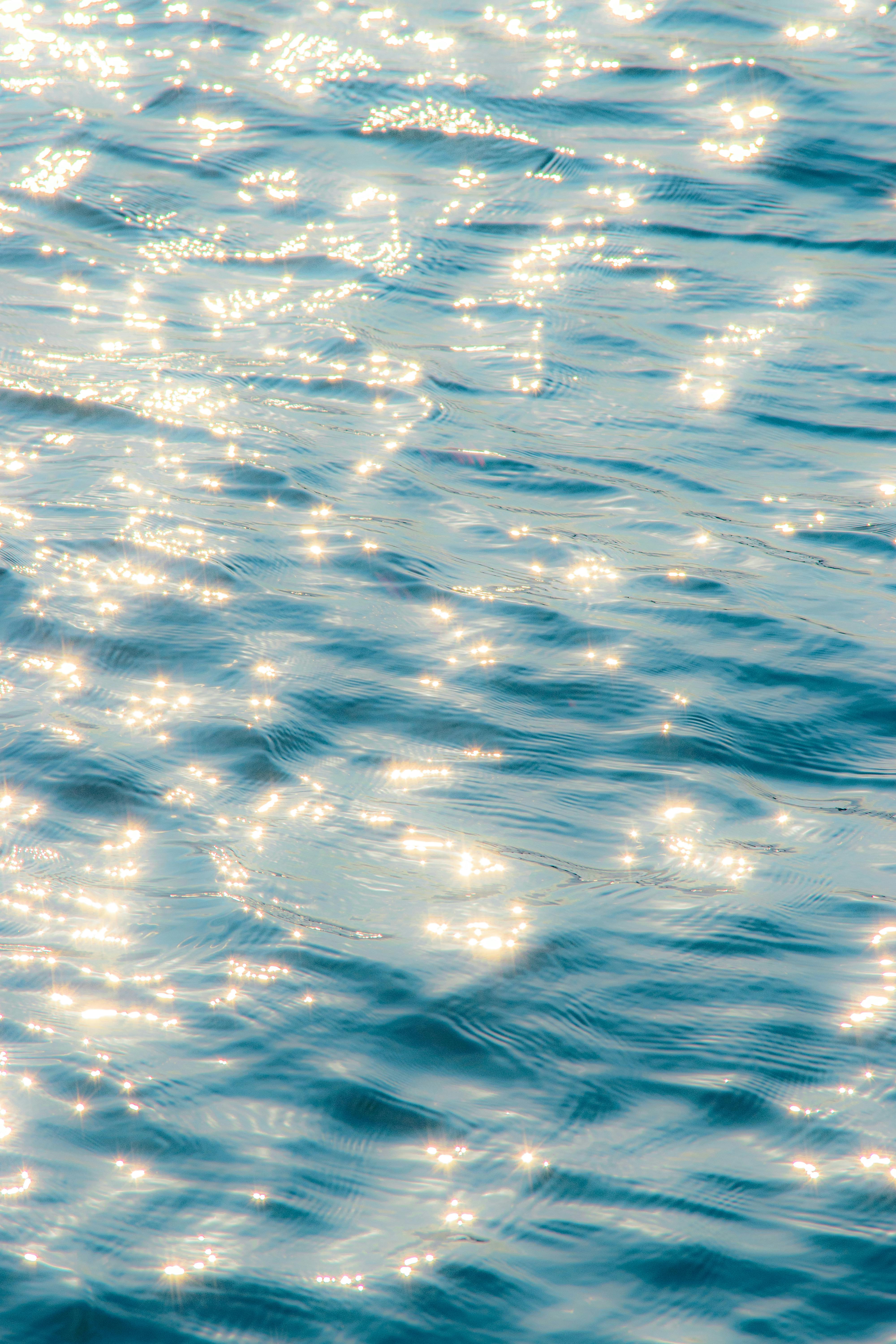Serene image of sunlight sparkling on a gentle water surface, evoking tranquility and calm.