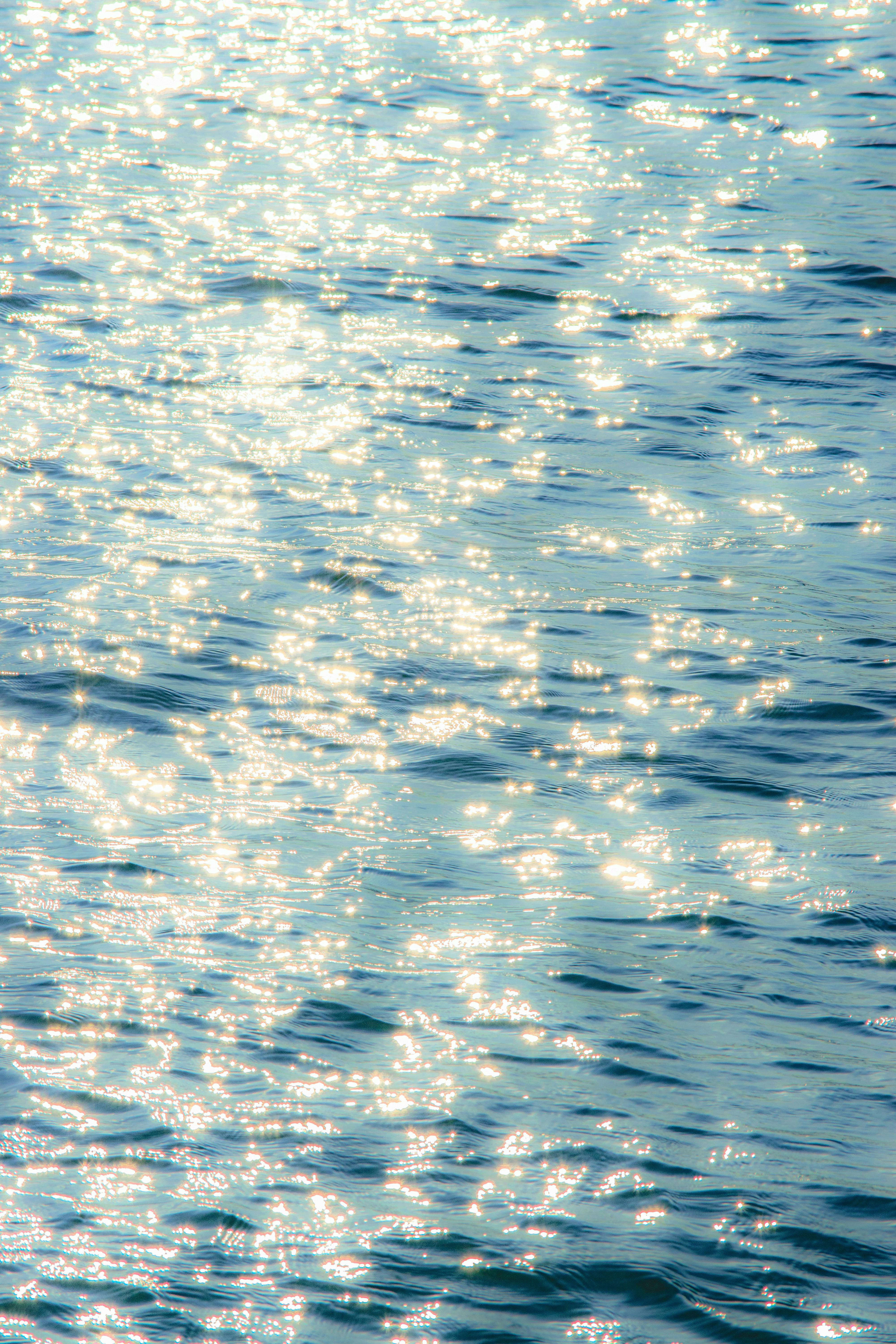 Bright sunlight creates a sparkling effect on ocean waves, capturing a serene and tranquil moment.