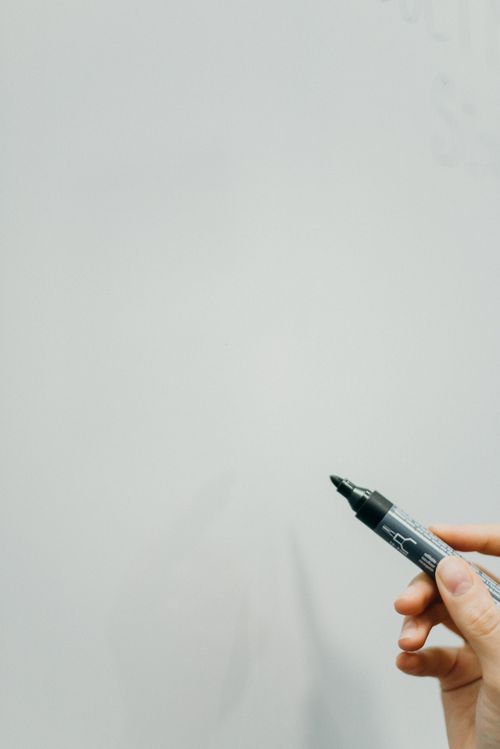 Free Close-up of hand holding black marker, ready to write on whiteboard. Stock Photo