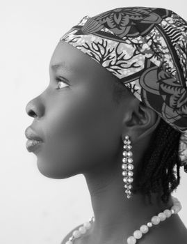 Elegant black and white portrait of a woman wearing a patterned headscarf and pearl earrings.