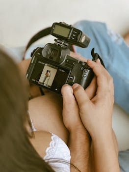 A photographer checks a couple's portrait on a camera screen, capturing intimate moments.