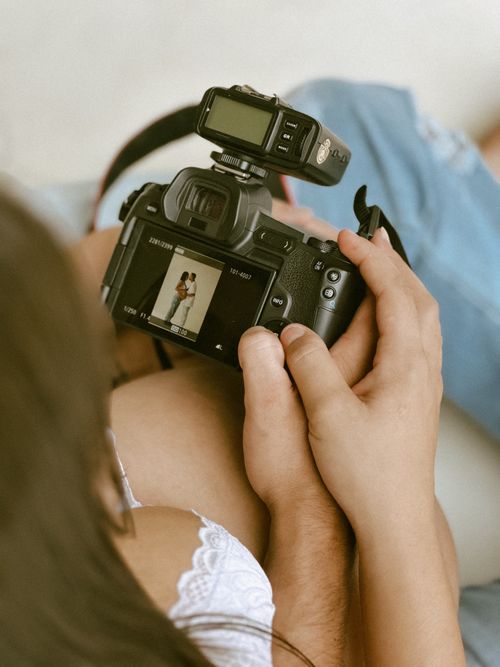 Free A photographer checks a couple's portrait on a camera screen, capturing intimate moments. Stock Photo