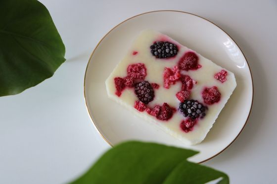 Slab of frozen white yogurt studded with raspberries and blackberries on a gold-rimmed plate