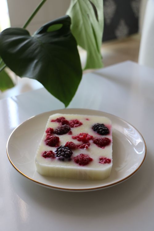 Free Plate with yogurt dessert topped with raspberries and blackberries, on a bright table. Stock Photo
