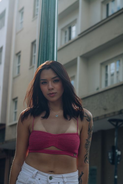 Free Young woman posing outdoors in urban setting wearing pink top. Stock Photo
